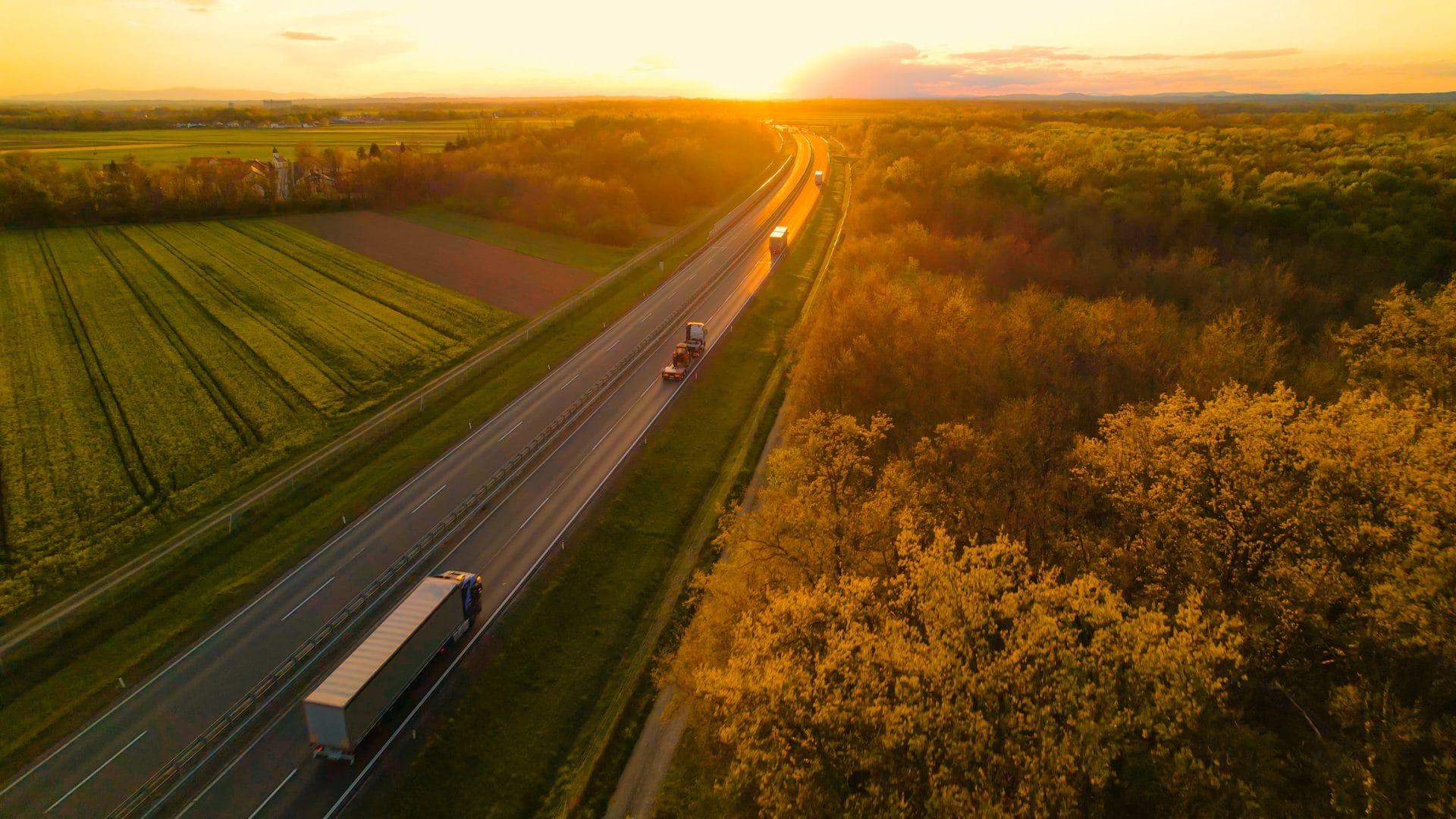 Aerial view of a highway running through farmland at golden hour.